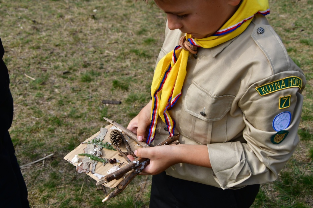Malý skaut drží v ruce obrázek z nalepených přírodnin.